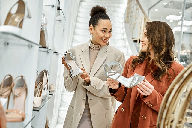 Dos amigas revisando zapatillas en una boutique de lujo.