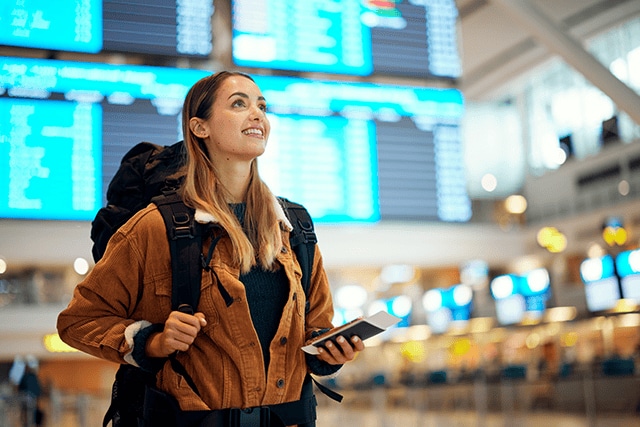 Mujer en la sala de salidas de un aeropuerto, esperando su vuelo.