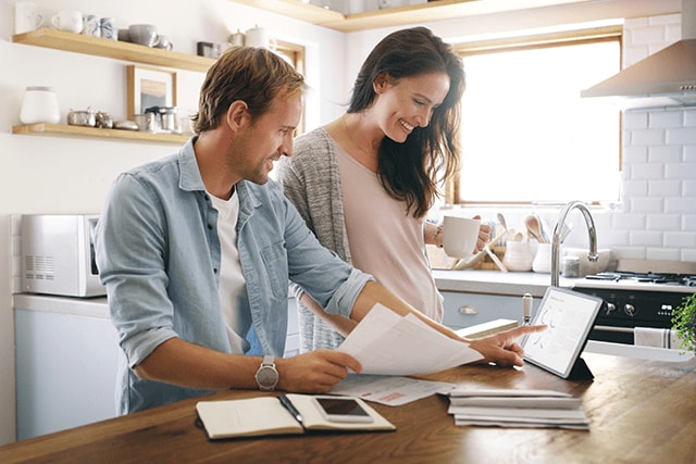 Pareja en casa revisando documentos en la encimera de la cocina.