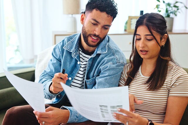 Una pareja revisa unos papeles en el sofá.