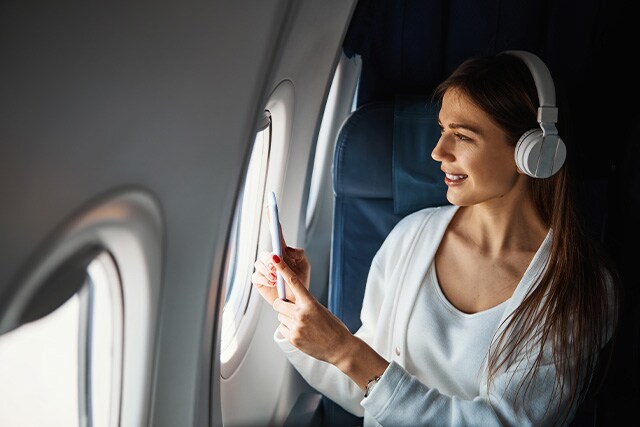 Mujer dentro de un avión, tomando una foto a través de la ventanilla.
