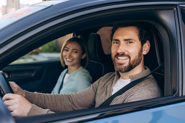 Pareja sonriendo a través de la ventanilla de un auto.