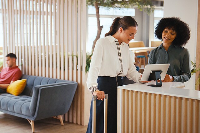 Mujer registrándose en la recepción de un hotel.