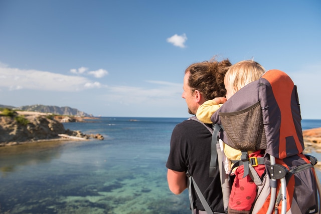 Padre e hija en una mochila portabebés contemplando el paisaje.