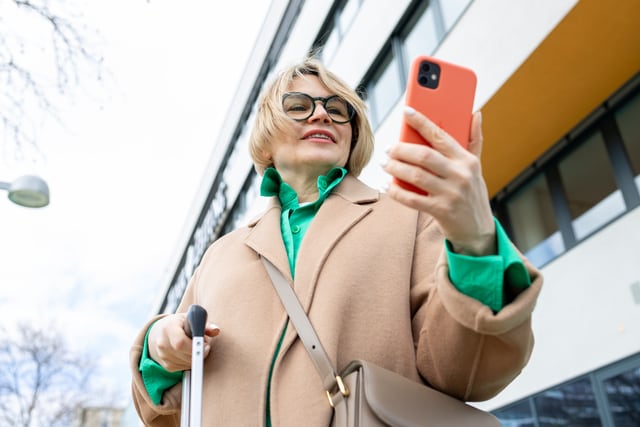 Mujer vistiendo ropa moderna a mientras habla por teléfono fuera de un edificio.