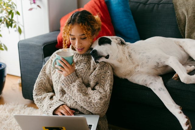 Mujer sentada en el suelo de su sala de estar usando su ordenador portátil.