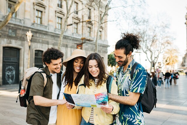 Grupo de jóvenes turistas usando un mapa en el Paseo de Las Ramblas de Barcelona, España.