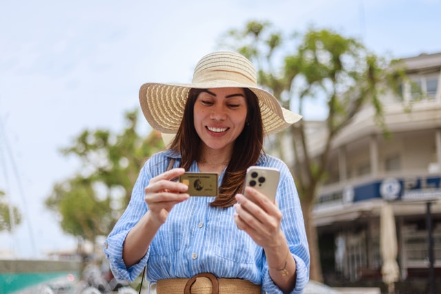 Mujer pagando con una tarjeta en su celular.