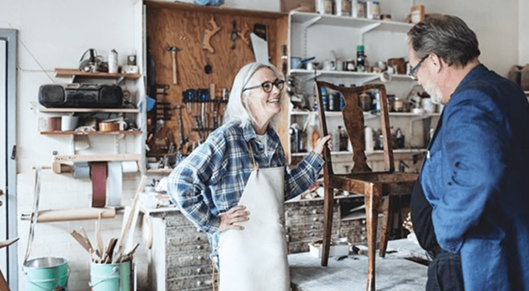 Mujer mostrando mueve de madera en taller de carpintería
