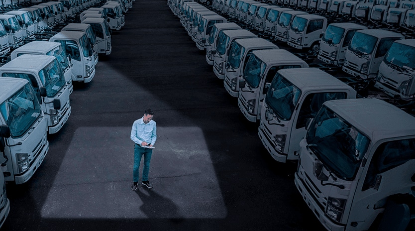 Hombre revisando sus notas en medio de una flotilla de camiones.