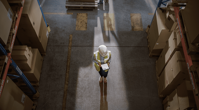 Persona revisando sus notas en medio de una bodega.