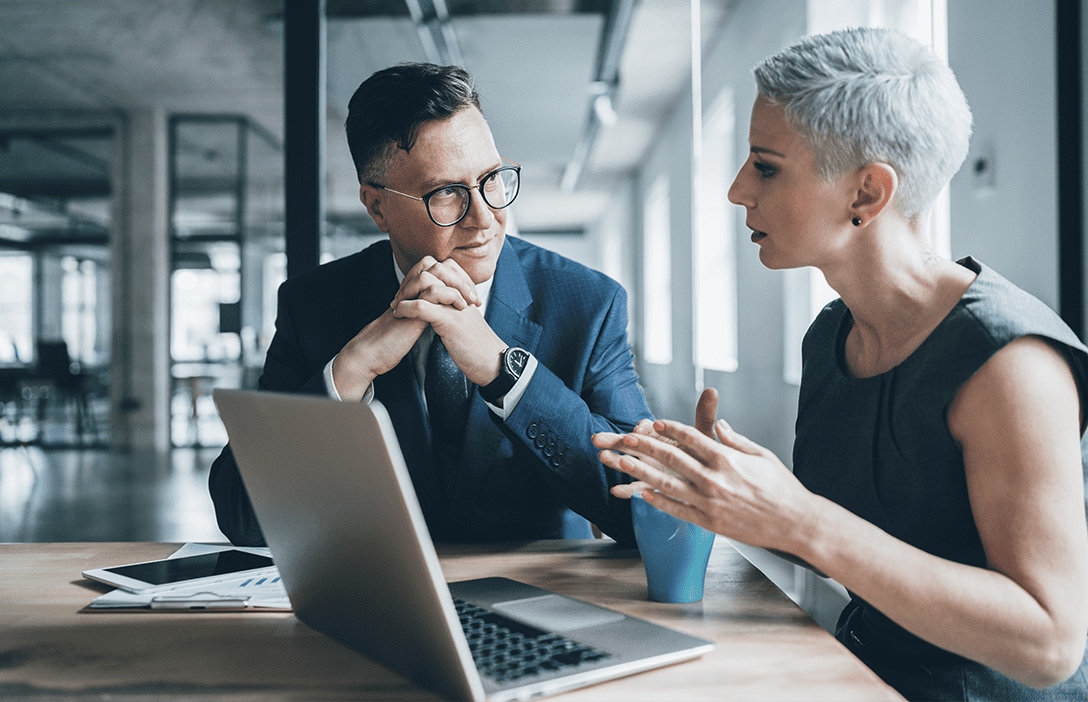 Hombre y mujer en plática de negocios en oficina.