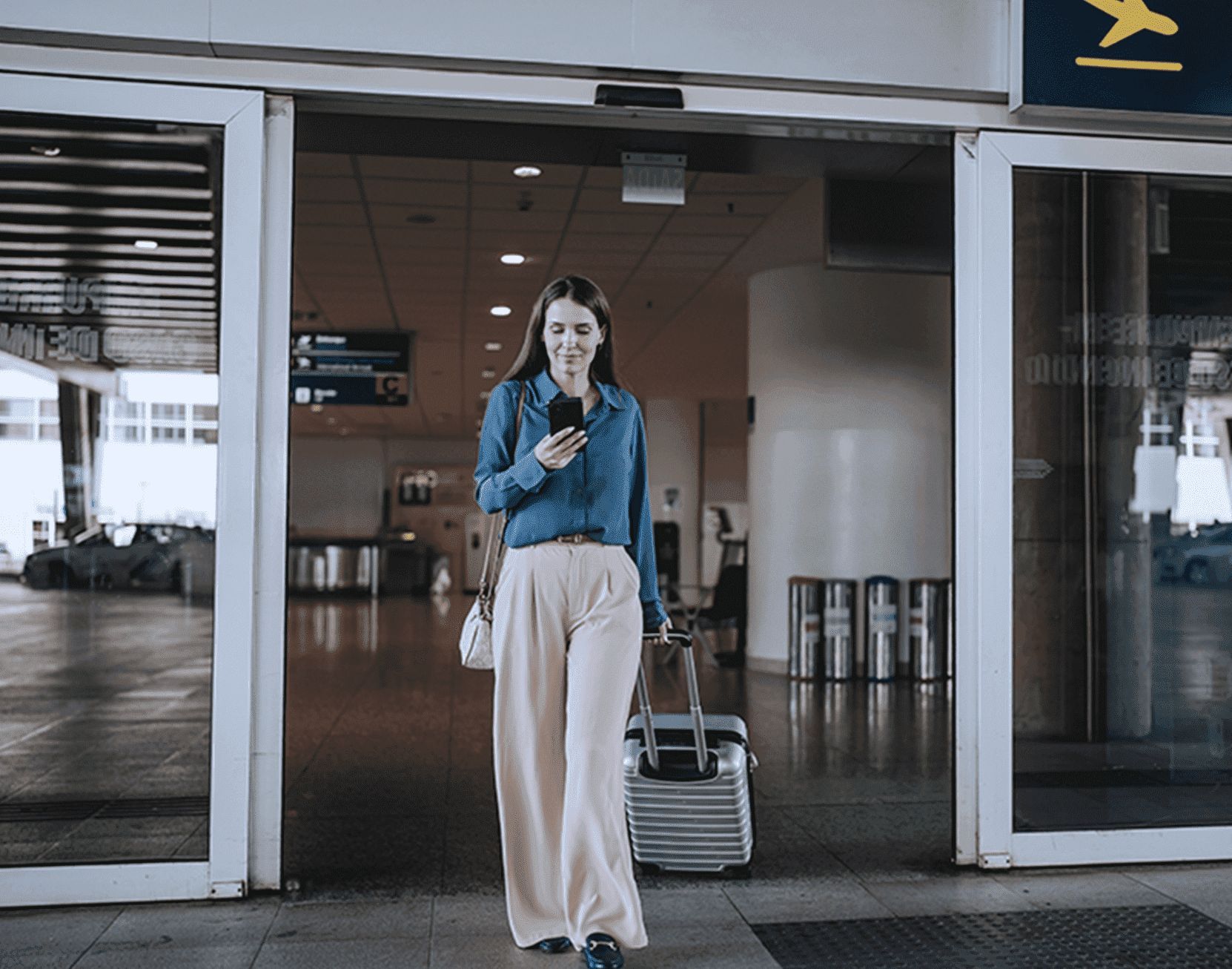 Mujer saliendo de aeropuerto con equipaje.