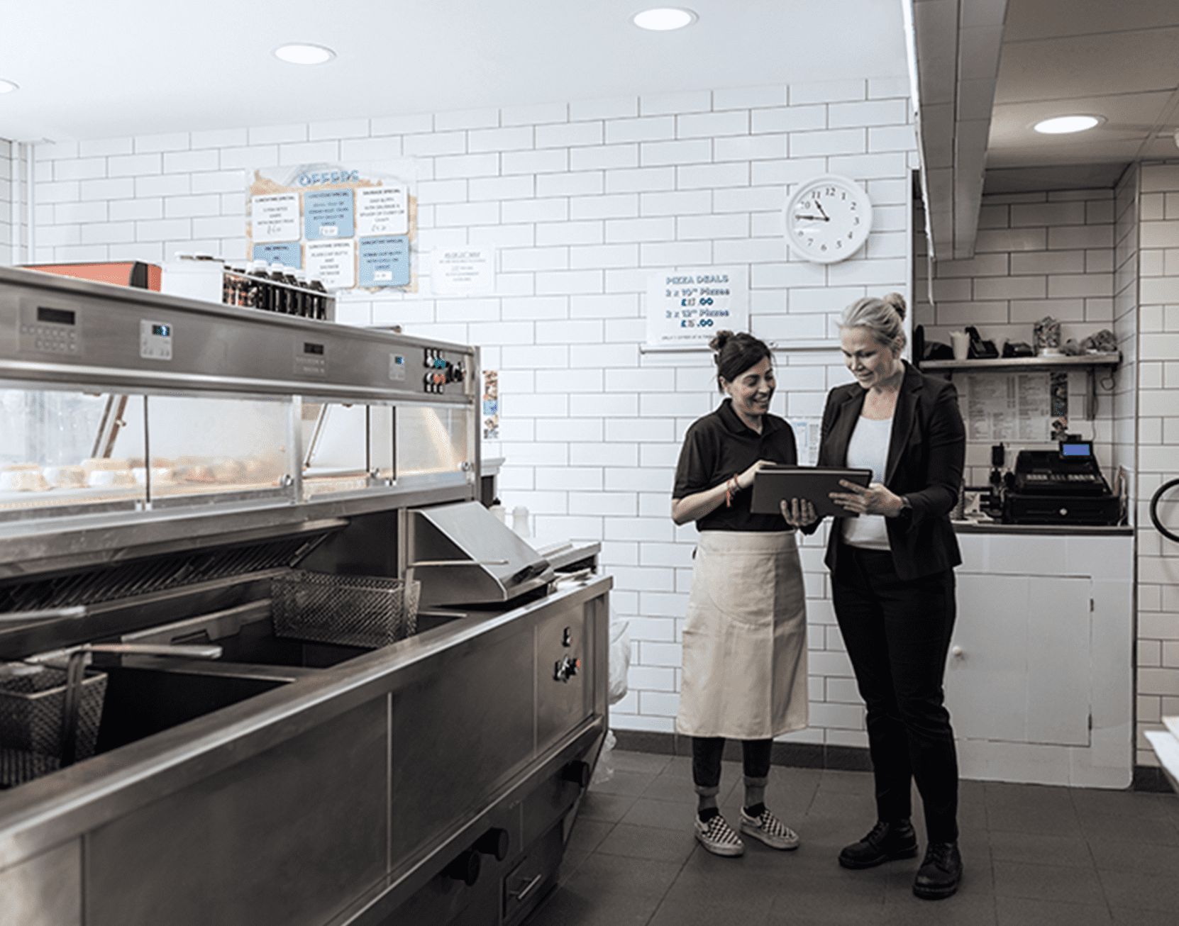 Dueña y empleada platicando en cocina.