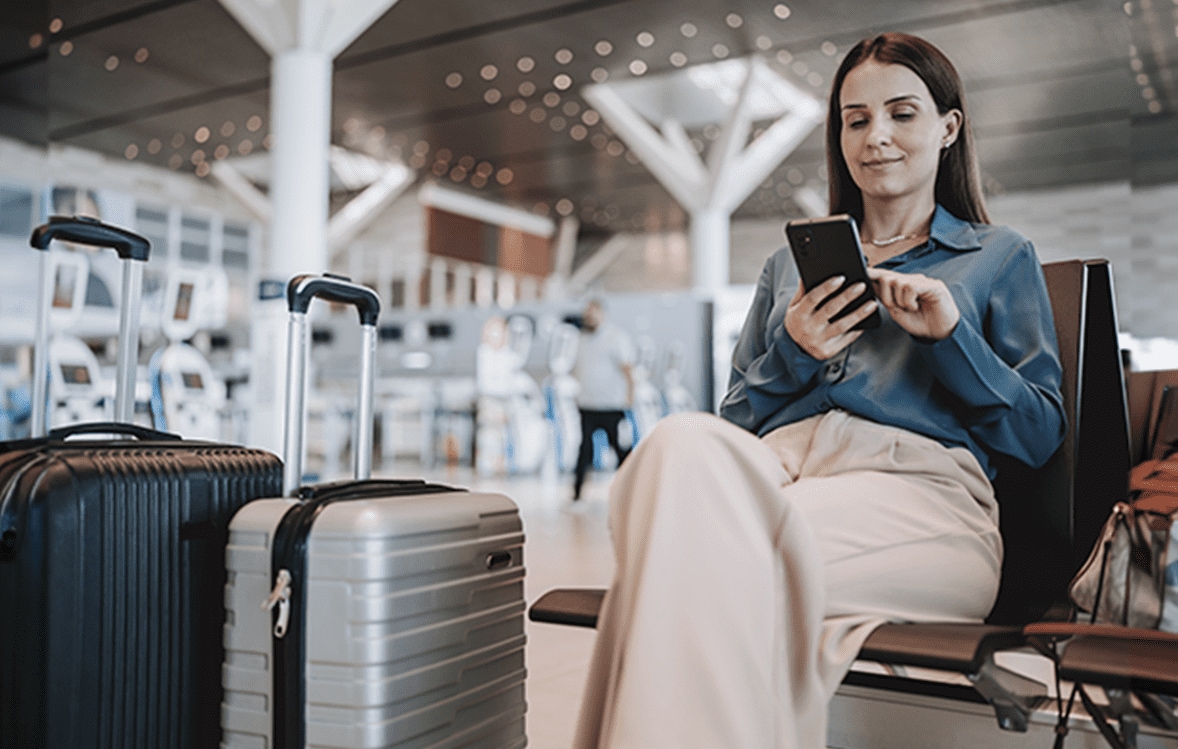 Mujer al teléfono esperando sentada en la sala de abordar.                    