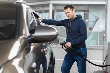 Persona poniendole gasolina a su coche pagando con tarjeta American Express