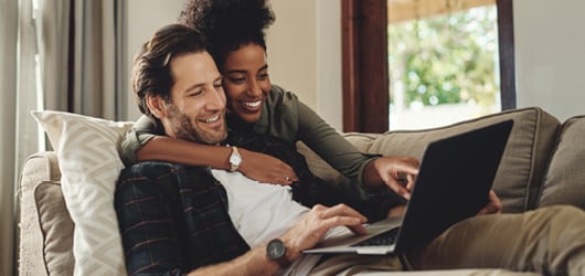 A couple sitting together and looking at a laptop