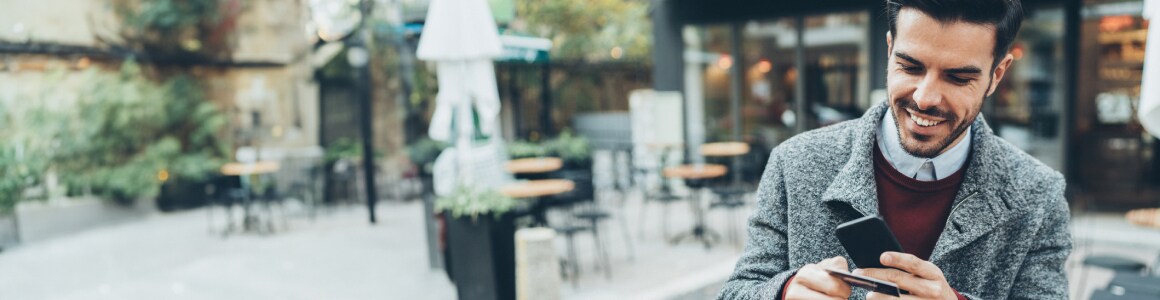 Homme regardant un téléphone et une carte de crédit en souriant