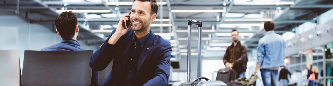 Homme souriant en parlant au téléphone dans un aéroport