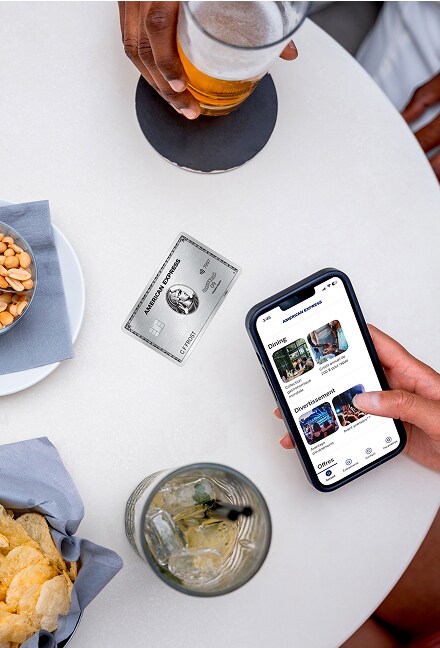 Overhead shot of table with food, and  a phone with the Amex Experiences App open    