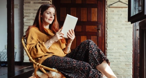 Woman sitting back in chair, looking at her tablet