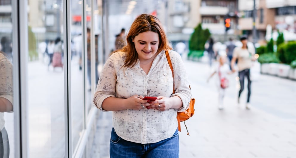 Woman walking and smiling while looking at phone