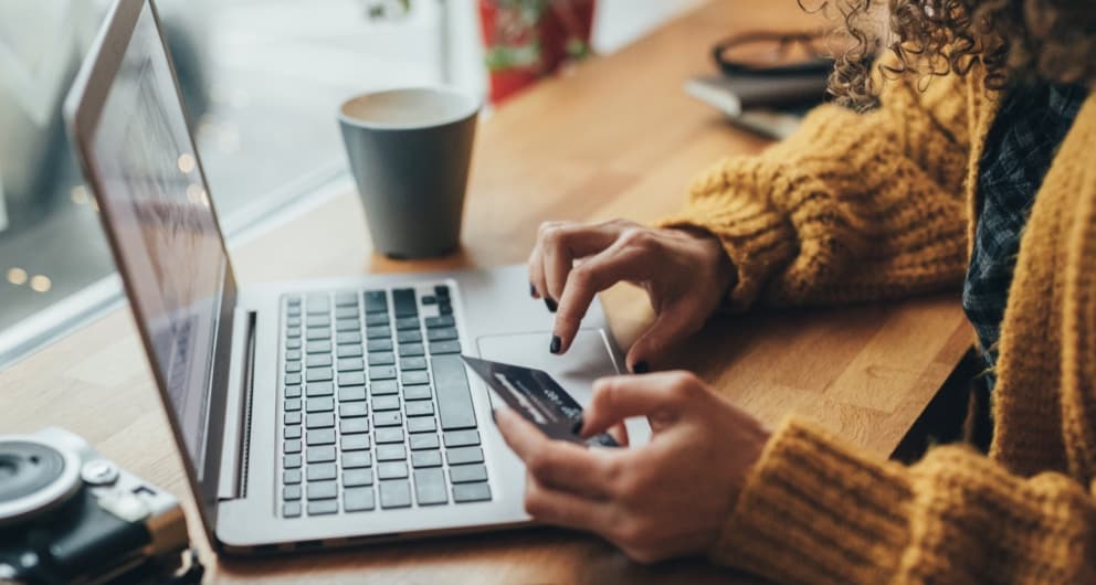 Woman typing credit card information into laptop