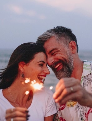 a man and a woman are laughing with sparklers in their hands
