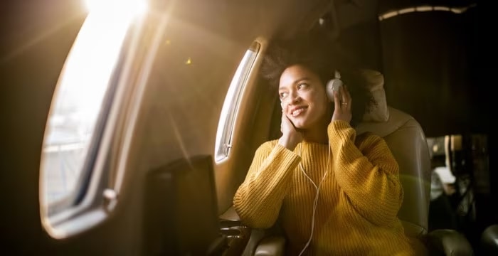 a woman is sitting on an airplane wearing headphones and listening to music .