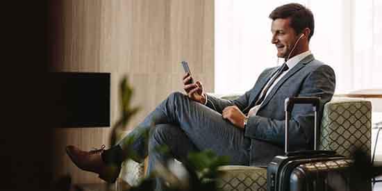 Suited man with luggage in airport lounge on his phone 