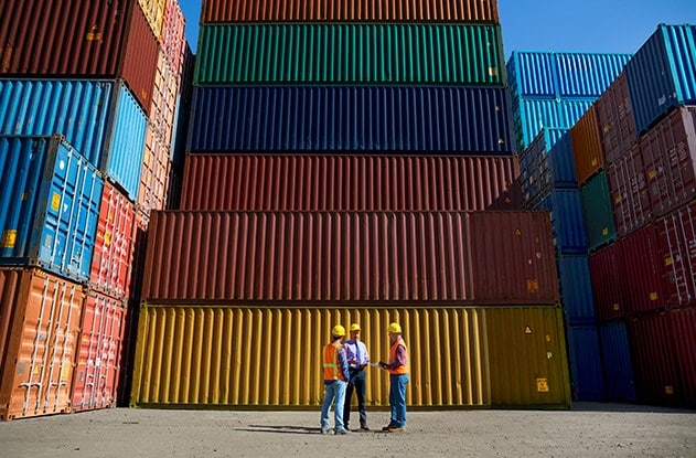 Woman working at a garment factory checking a row of orange and blue t-shirts.
