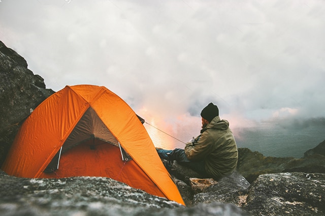 Father and son in a yard sitting on soccer balls chatting.