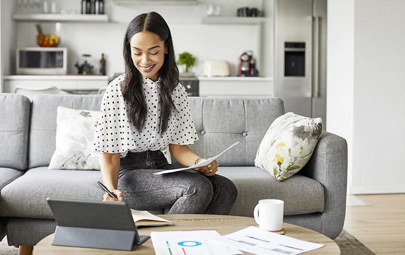 ragazza seduta sul divano di casa prende appunti su agenda