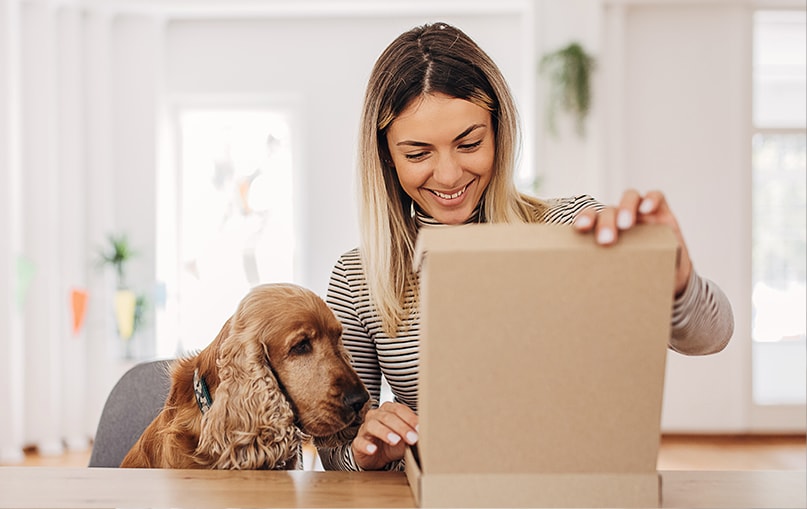 ragazza apre un pacco regalo in compagnia del suo cane  