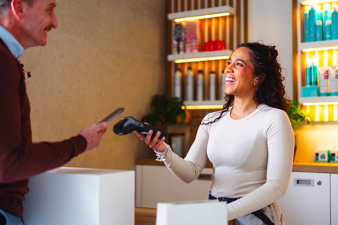 Customer paying with phone and tapping on terminal at a salon