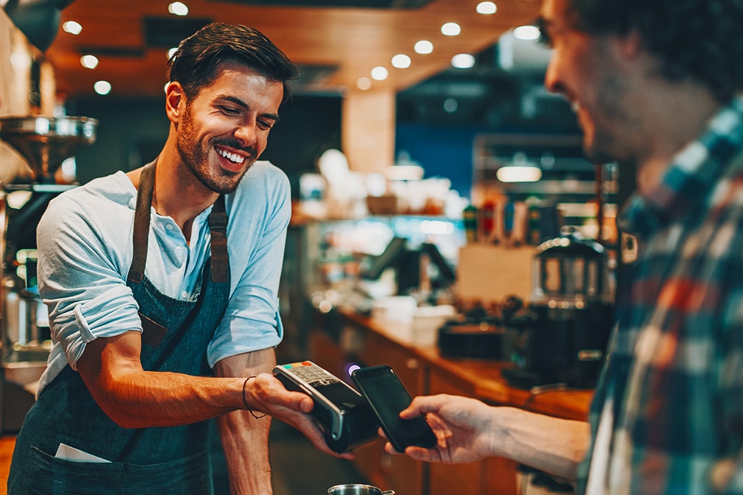 Customer paying with phone and tapping on terminal at a coffee shop