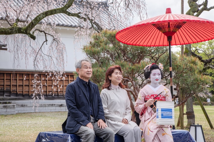 専用エリアでは紅しだれ桜が白壁に映え、芸舞妓との記念撮影に笑顔が広がります