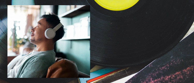 ソファにもたれ目をつぶりヘッドフォンで音楽を楽しむ男性