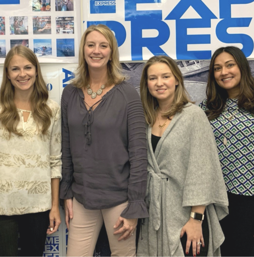 Five colleagues pose before an array of American Express posters