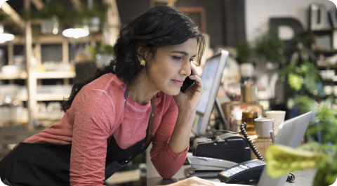 La dueña de una tienda de plantas hablando sobre el teléfono con su proveedor de pagos.