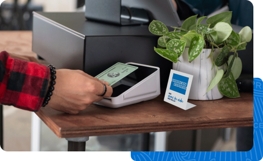 Un cliente que usa su americano Tarjeta exprés para completar su compra. Cerca del registro hay un letrero que dice "American Express. No lo hagas
negocio sin él".