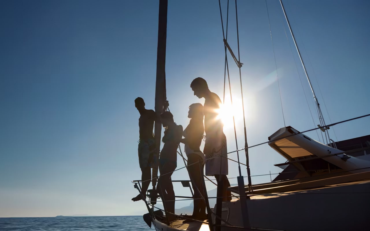 Groep mensen aan boord van zeilboot bij zonsondergang