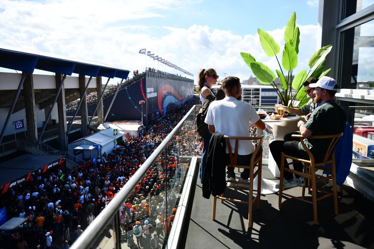 The American Express Private Lounge, outside deck with three people at a hight table and a big plant