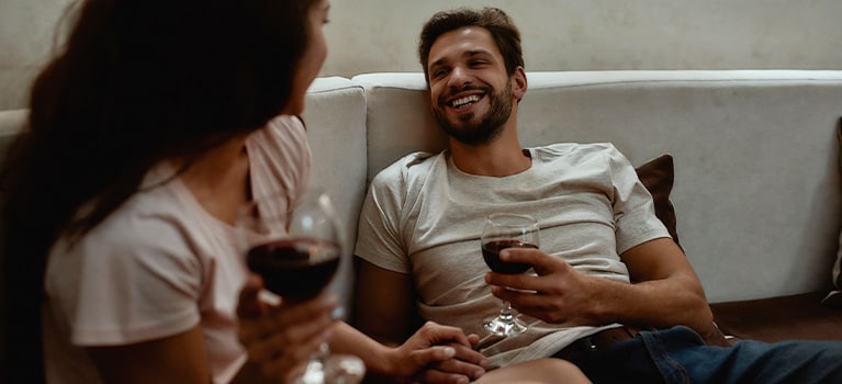 Casal tomando vinho no sofá.