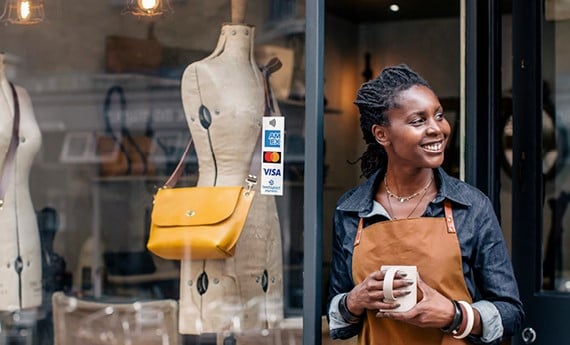 Business owner standing next to storefront with Amex decal in window