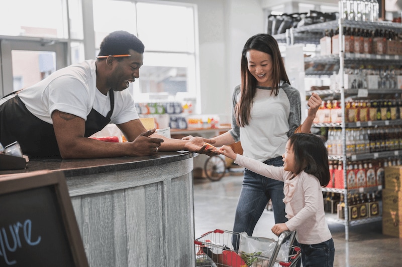 Merchant handing young child a cheese sample