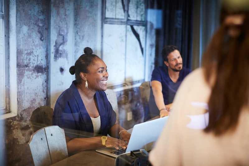 person sitting at table with laptop and smiling