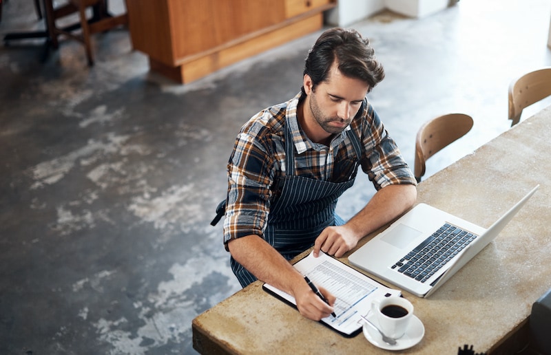 coffee shop owner sitting at table with laptop