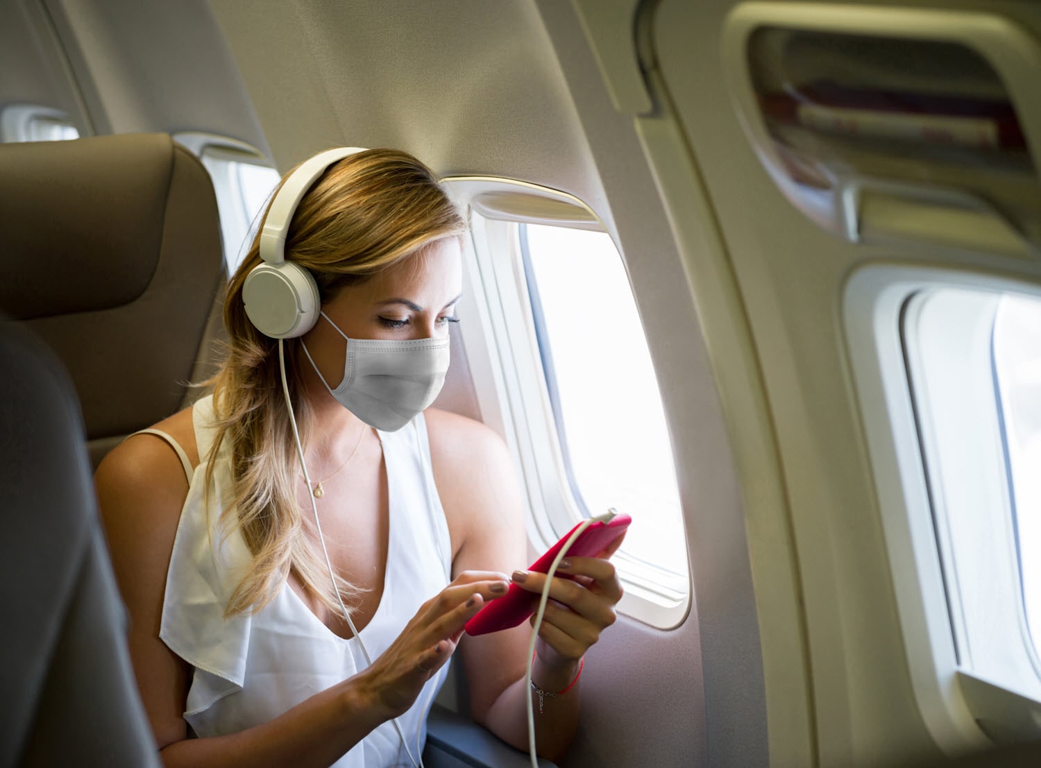 A woman wearing a face mask on an airplane