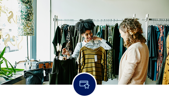 Two woman in a boutique store shopping for clothes.